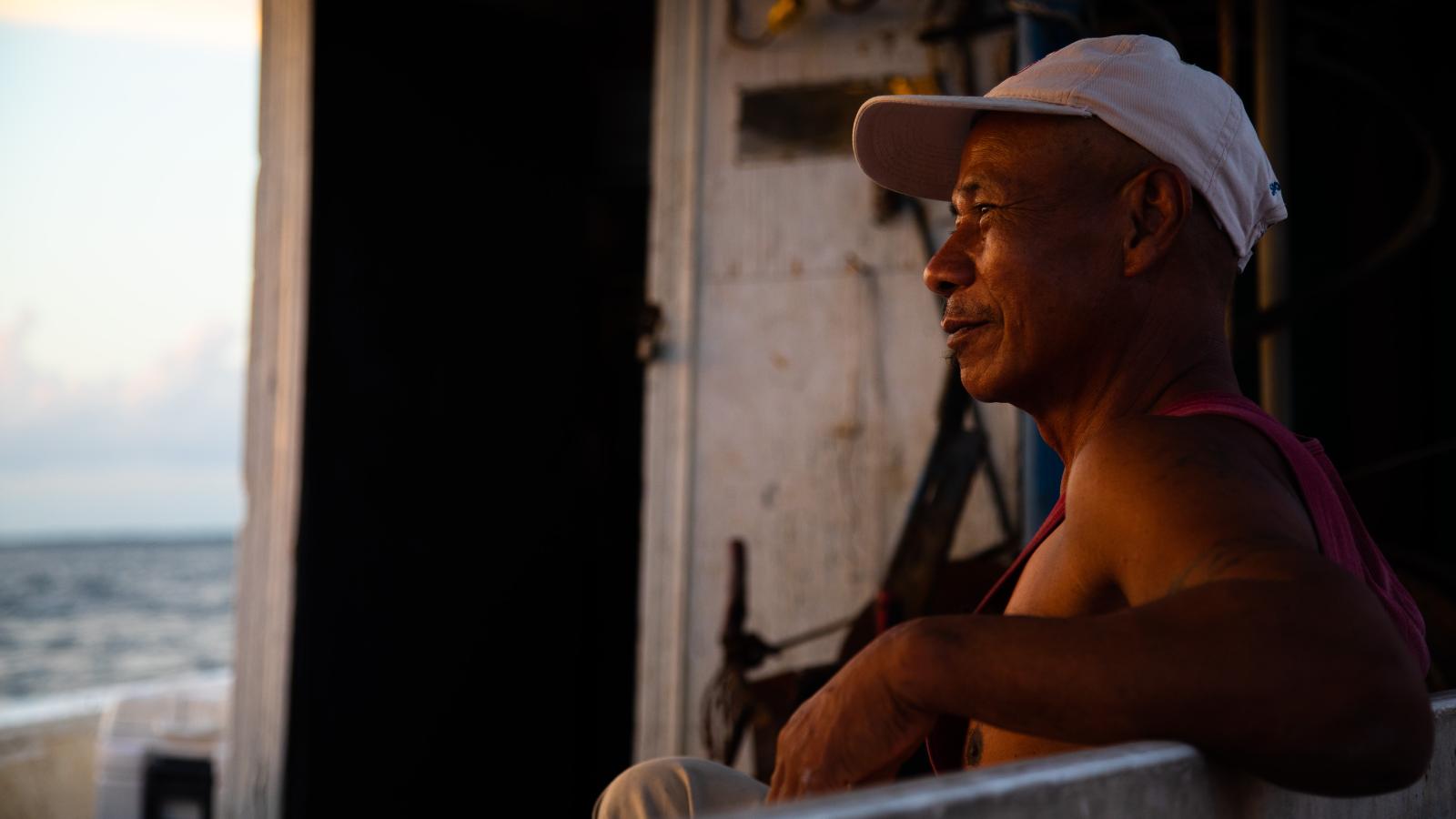 A deck hand sits and takes a break on the boat.