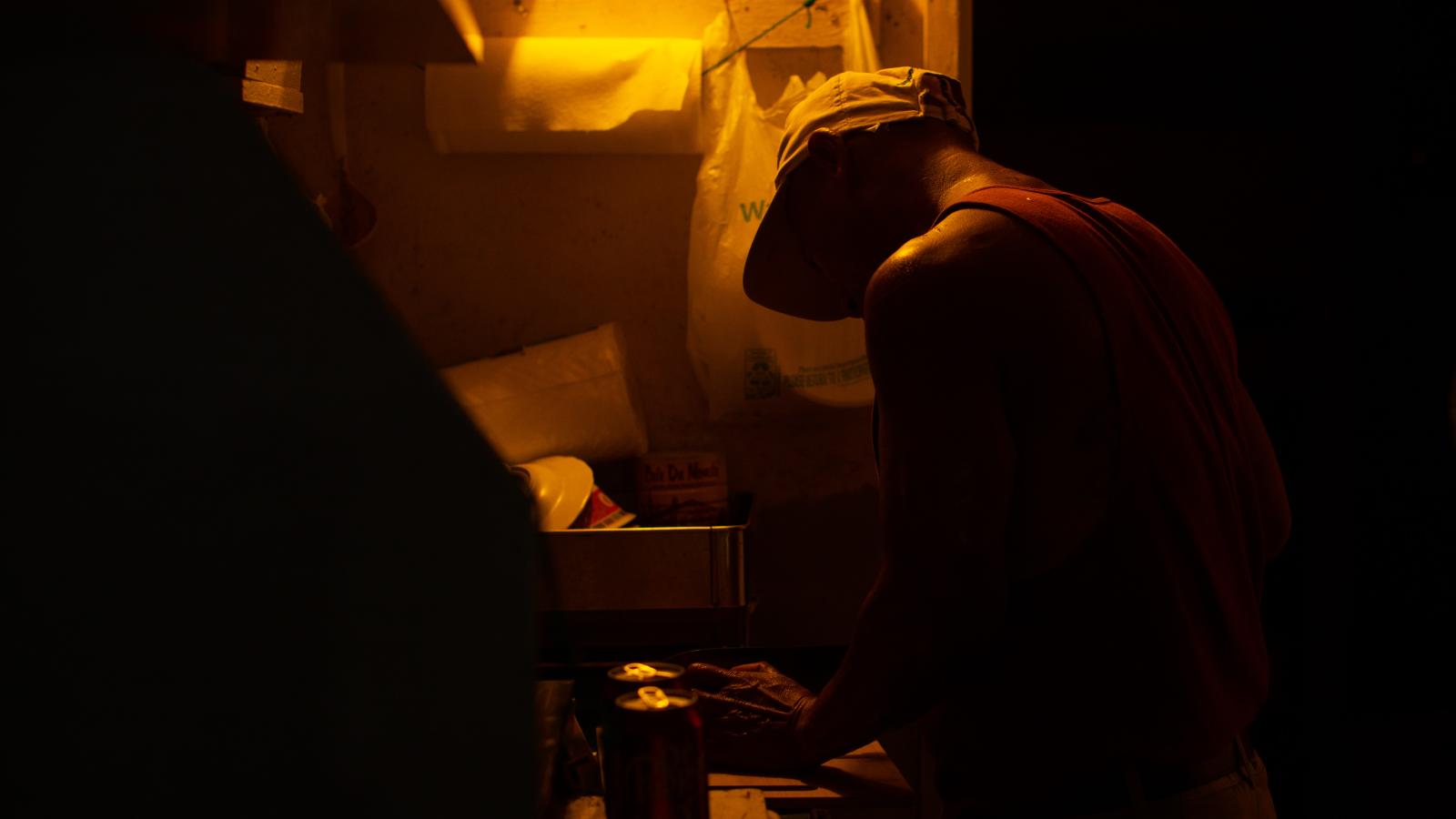 A dimly lit kitchen as a deck hand prepares a quick meal.